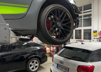 Einblick in die große Werkshalle von Dr. Car in Heilbronn, mit einem grauen AMG Mercedes Supersportwagen auf der Hebebühne und weiteren Fahrzeugen in der Bearbeitung.