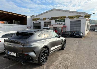Ein grauer Aston Martin DBX steht nach der professionellen Aufbereitung abholbereit vor dem Eingang der Kfz-Lackiererei Dr. Car in Heilbronn.