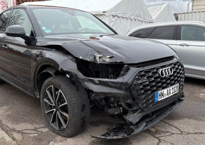 Nahaufnahme eines schwarzen Audi mit Frontschaden, fotografiert aus einem anderen Winkel in der Dr. Car Werkstatt Heilbronn, bereit für die Karosseriereparatur.
