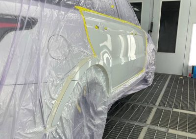 Detailansicht eines für die Lackierung vorbereiteten Fahrzeugs in der Lackierkabine von Dr. Car Heilbronn, inklusive professioneller Abklebung der Karosserie.