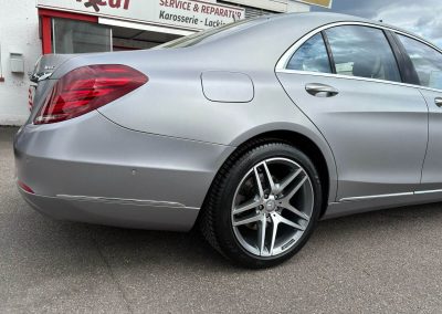 Seitenansicht einer Mercedes S-Klasse in Matt-Silber vor dem Werkstattgebäude von Dr. Car in Heilbronn – Spezialist für Karosserie und Lackierung.