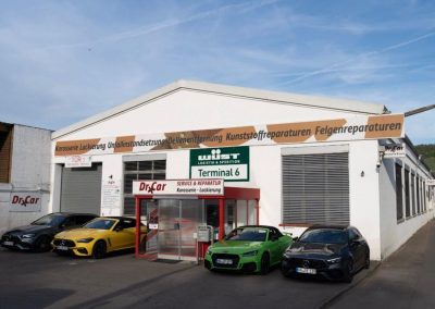 Außenansicht der Dr. Car Werkstatt und Lackiererei in Heilbronn mit mehreren hochwertigen Sportwagen und Premiumfahrzeugen davor.