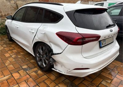Weißer Ford Focus mit Streifschaden und Beule an der hinteren Seitenwand links vor der professionellen Karosserieinstandsetzung bei Dr. Car in Heilbronn.