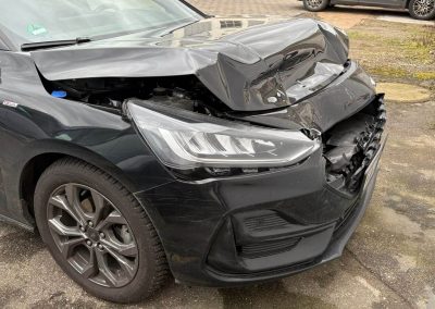 Schwarzer Ford mit massivem Frontalschaden (Stoßstange, Motorhaube, Scheinwerfer) auf dem Gelände der Kfz-Werkstatt Dr. Car in Heilbronn zur Karosserieinstandsetzung.