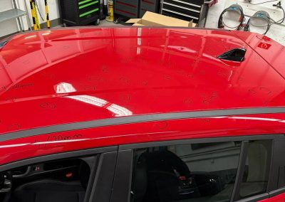 Nahaufnahme eines roten Kfz-Dachs, übersät mit schwarzen Markierungen für Hagelschaden-Dellen, die für die Reparatur bei Dr. Car in Heilbronn vorbereitet sind.