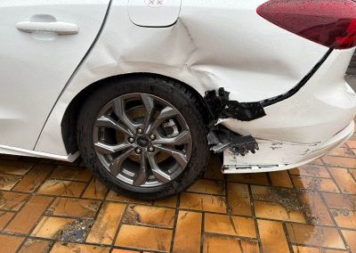 Weißer Ford mit massivem Unfallschaden hinten rechts: Eingedrückter Kotflügel, abgerissene Heckstange und beschädigte Radhausverkleidung vor der Karosserie-Instandsetzung bei Dr. Car in Heilbronn.