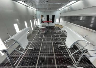 Professionell angeordnete Karosserieteile in der sauberen Lackierkabine von Dr. Car Heilbronn, bereit für die Grundierung oder Lackierung.