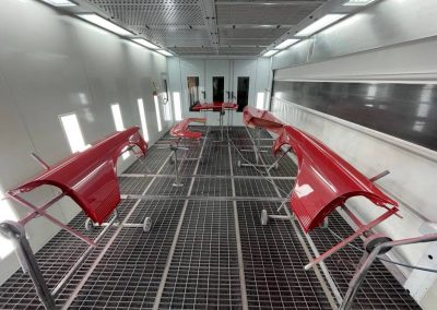 Frisch lackierte rote Karosserieteile und Kotflügel während des Trocknungsprozesses in der modernen Lackierkabine von Dr. Car in Heilbronn.