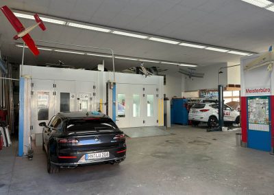 Innenansicht der modernen Kfz-Meisterfachwerkstatt Dr. Car in Heilbronn mit Lackierkabine, Hebebühne und Meisterbüro – Professionelle Autolackierung und Karosseriebau.