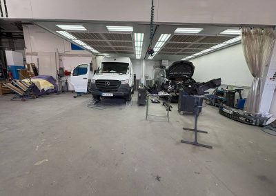 Einblick in den aktiven Werkstattbetrieb bei Dr. Car in Heilbronn – Instandsetzung eines Mercedes Sprinters und Karosseriearbeiten an weiteren Kundenfahrzeugen unter professioneller Werkstattbeleuchtung.