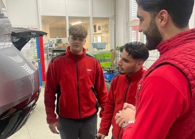 Das Team von Dr. Car in Heilbronn bespricht die Vorgehensweise für die Lackreparatur an einem grauen Wagen in der Kfz-Werkstatt.