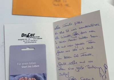 Ein Mitarbeiter der Kfz-Lackiererei Dr. Car in Heilbronn schreibt eine persönliche Glückwunschkarte für einen Kunden am Empfangstresen.