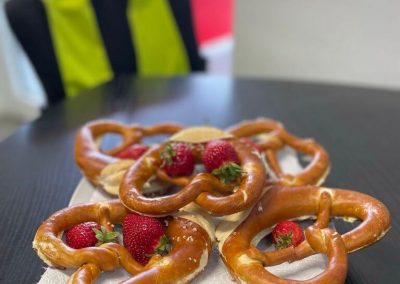 Frische Butterbrezeln und Erdbeeren als Snack für wartende Kunden im gemütlichen Empfangsbereich der Dr. Car Werkstatt Heilbronn.