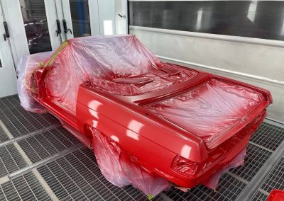 Rote Neulackierung einer Oldtimer-Karosserie in der professionellen Lackierkabine von Dr. Car in Heilbronn, mit präziser Abklebung der nicht zu lackierenden Teile.