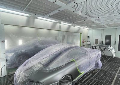 Ein Porsche in der Lackierkabine von Dr. Car Heilbronn, sorgfältig maskiert und vorbereitet für eine professionelle Reparaturlackierung.