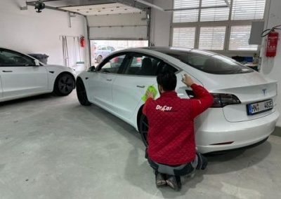 Glänzendes Tesla Model nach der professionellen Unfallreparatur und Hochglanzlackierung abholbereit vor der Kfz-Werkstatt Dr. Car in Heilbronn (Fachbetrieb für E-Mobilität).