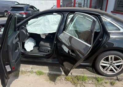 Schwarze Audi-Limousine mit schwerem seitlichem Streifschaden und ausgelösten Kopfairbags steht vor der Kfz-Werkstatt Dr. Car in Heilbronn zur Unfallinstandsetzung.